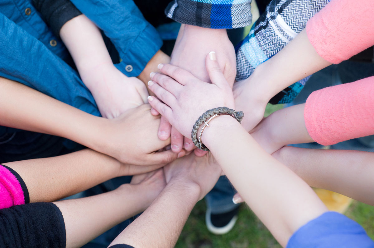 Kids putting their hands on top of each other in a huddle