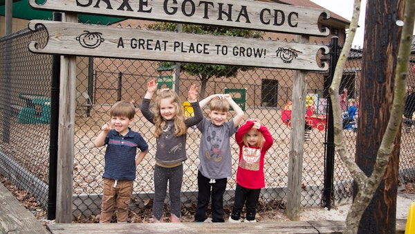 Kids standing in front of the Saxe Gotha CDC wooden sign