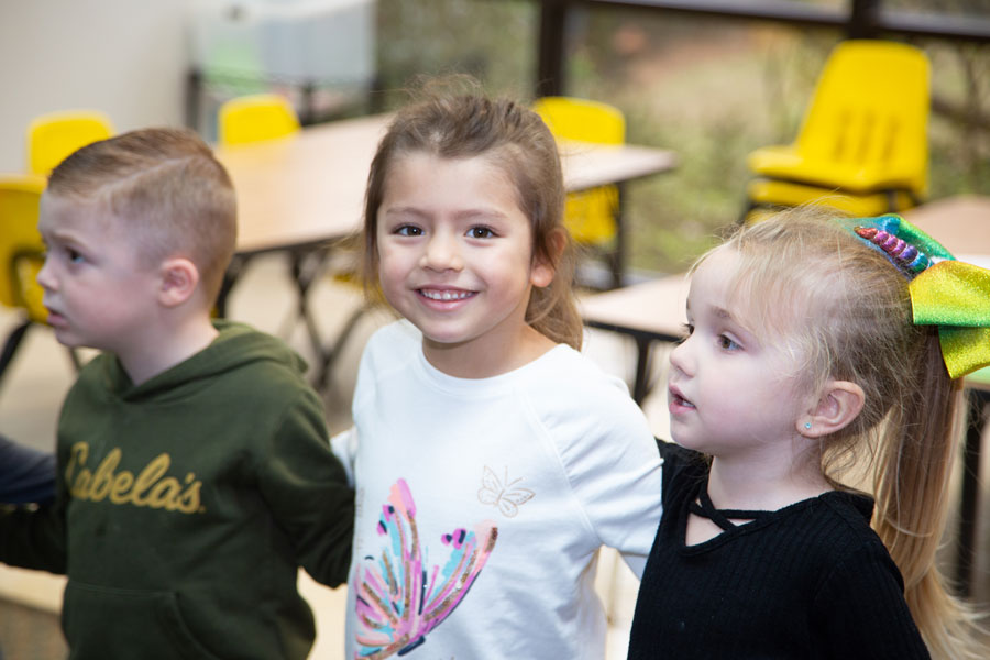 Three kids at CDC with one girl looking at the camera and smiling